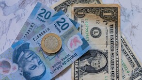 Dólar estadounidense junto a un billete y moneda de pesos mexicanos.