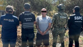Hombre esposado y con los ojos censurados por un recuadro negro en medio de oficiales de Michoacán, Morelos y la Marina