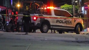 Oficiales y patrulla de la Policía de Tlaquepaque con la sirena encendida detrás de una cinta policiaca amarilla en medio de una calle