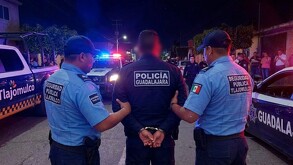 Policía de Guadalajara siendo arrestado por dos policía de Tlajomulco en medio de la calle con patrullas y personas alrededor