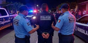 Policía de Guadalajara siendo arrestado por dos policía de Tlajomulco en medio de la calle con patrullas y personas alrededor