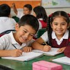 Niños de primaria en un salón de clases sonriendo a la cámara. Beca Rita Cetina.