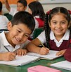 Niños de primaria en un salón de clases sonriendo a la cámara. Beca Rita Cetina.
