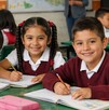 Niños de primaria en un salón de clases sonriendo a la cámara. Beca Rita Cetina.