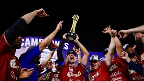 Jugadores de los Charros de Jalisco celebran con júbilo en el campo, mientras uno de ellos levanta el trofeo de campeones hacia el cielo nocturno.