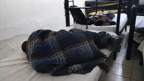 Hombre acostado en cama en refugio en Monterrey.