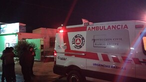 Se observa a varias personas en medio de la calle, es de noche, hay una cinta de precaución.