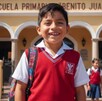 Niño con uniforme escolar feliz afuera de un plantel.