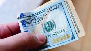 Dólar estadounidense siendo agarrado por una persona.