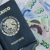 Dos pasaportes mexicanos uno encima del otro sobre varios billetes de 500 pesos sobre una mesa blanca