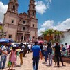 Catedral de San Juan de los Lagos con personas caminando en la plazuela con una fuente a un costado