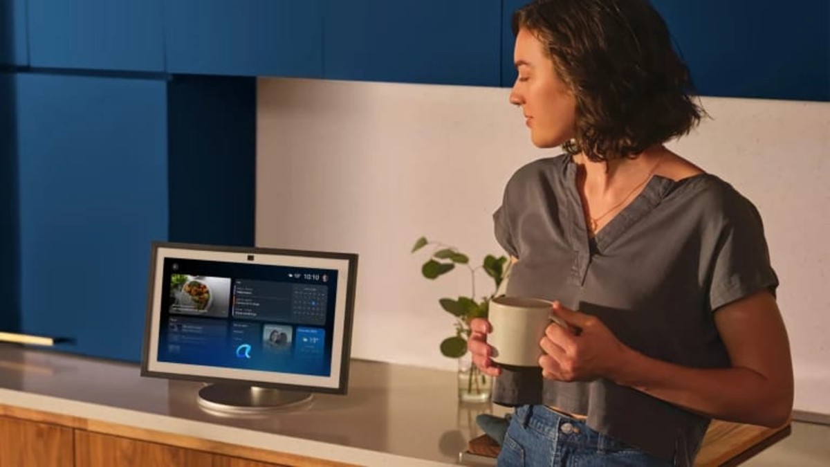 Una mujer con un dispositivo vinculado a Alexa+ mientras la mujer bebe sostiene una taza de café y conversa con Alexa+