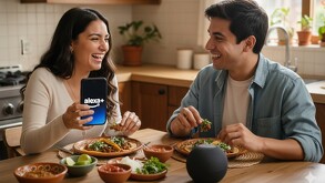 Pareja joven conversa con Alexa+ desde un teléfono celular mientras están en la cocina y comen comida mexicana