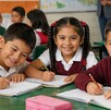 Niños de primaria en un salón de clases sonriendo a la cámara. Beca Rita Cetina.