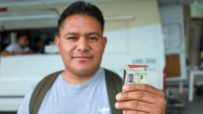 Persona sonríe y enseña su licencia de conducir del estado de Puebla.