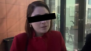 Se observa a una mujer de cabello corto, con ojos cubiertos y con blusa roja.