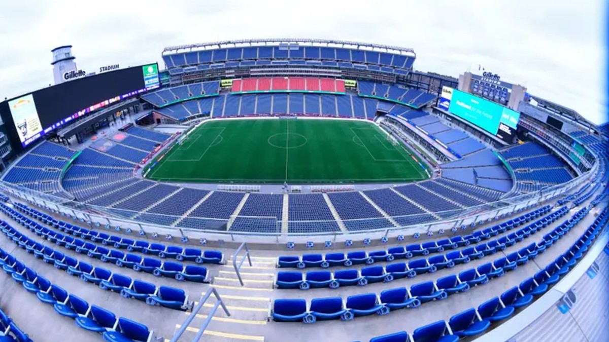 Una vista panorámica de gran angular desde las gradas superiores del Gillette Stadium, mostrando el campo de fútbol vacío y las pantallas gigantes.