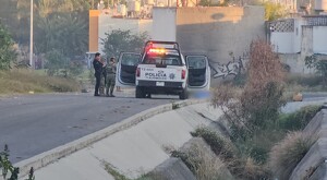 Patrulla de la Policía Municipal de Tlajomulco con oficiales y militares de la Guardia Nacional resguardando un cuerpo cubierto con una manta azul