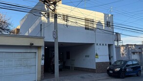 Se observa una fachada de casa clor beige con blanco.