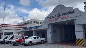 Se observa una fachada color gris con letras que dicen Policía Municipal y hay varios vehículos estacionados.
