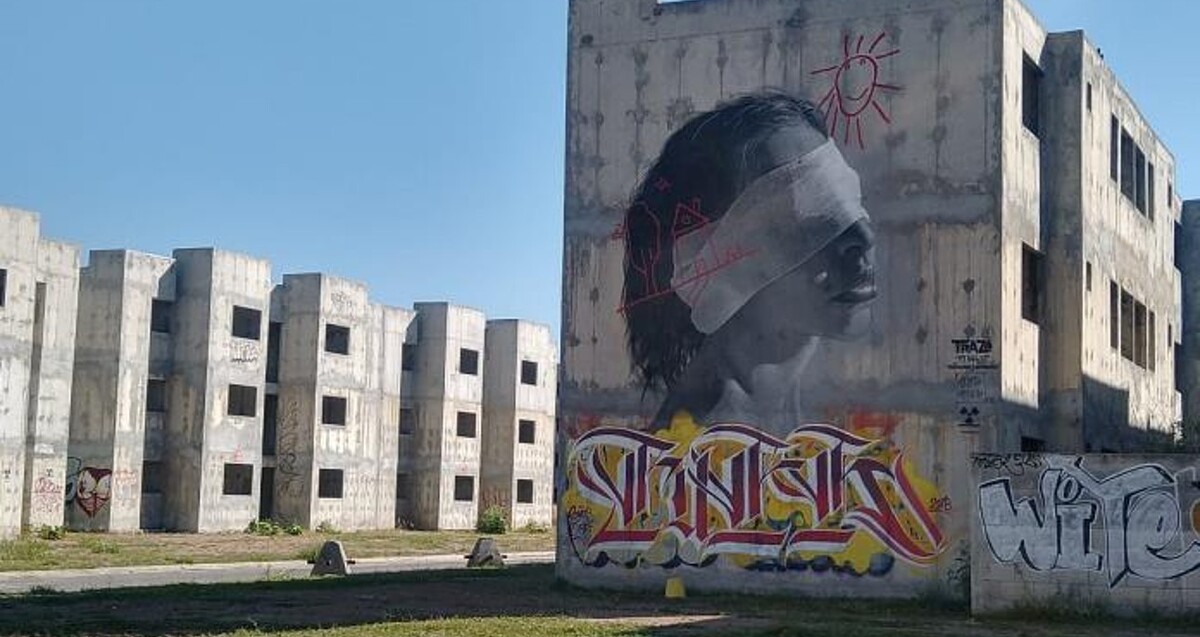 Grafitis pintados en el muro de un edificio de viviendas con otros edificios departamentales abandonados de fondo