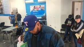 Se observa a varios hombres parados dentro de un cuarto color azul.