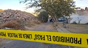 Cinta policiaca amarilla acordonando una zona de terrenos baldíos con patrullas de la Policía de Guadalajara de fondo