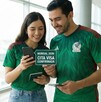 Pareja portando la camiseta de la Selección Nacional mientras observan su celular.