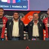 Cuatro hombres posan en una mesa de prensa del Atlas FC; dos jugadores visten la camiseta rojinegra y otros dos directivos usan chamarras del club.