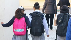 dos niñas con uniforme escolar y mochila caminan juntas a la escuela