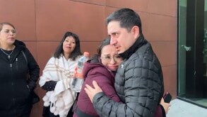 Se ven varias personas, entre ellas un hombre y una mujer que están abrazados.