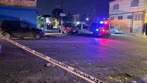 Se observa que es de noche, hay una cinta amarilla de precaución y unos carros estacionados.