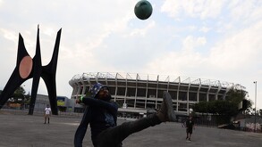Hombre jugando fútbol frente al Estadio Azteca previo al Mundial 2026.