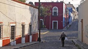 Un hombre camina sobre la calle empedrada del barrio de Analco, en Puebla capital.
