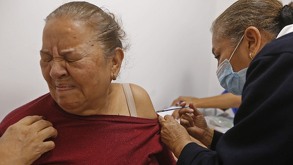 Mujer hace un gesto de dolor mientras es vacuada contra el sarampión.