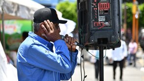 Hombre adulto se tapa los oídos al cantar frente a una bocina.