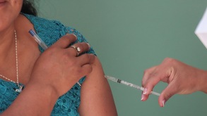 Mujer pone una vacuna contra el sarampión a una persona.