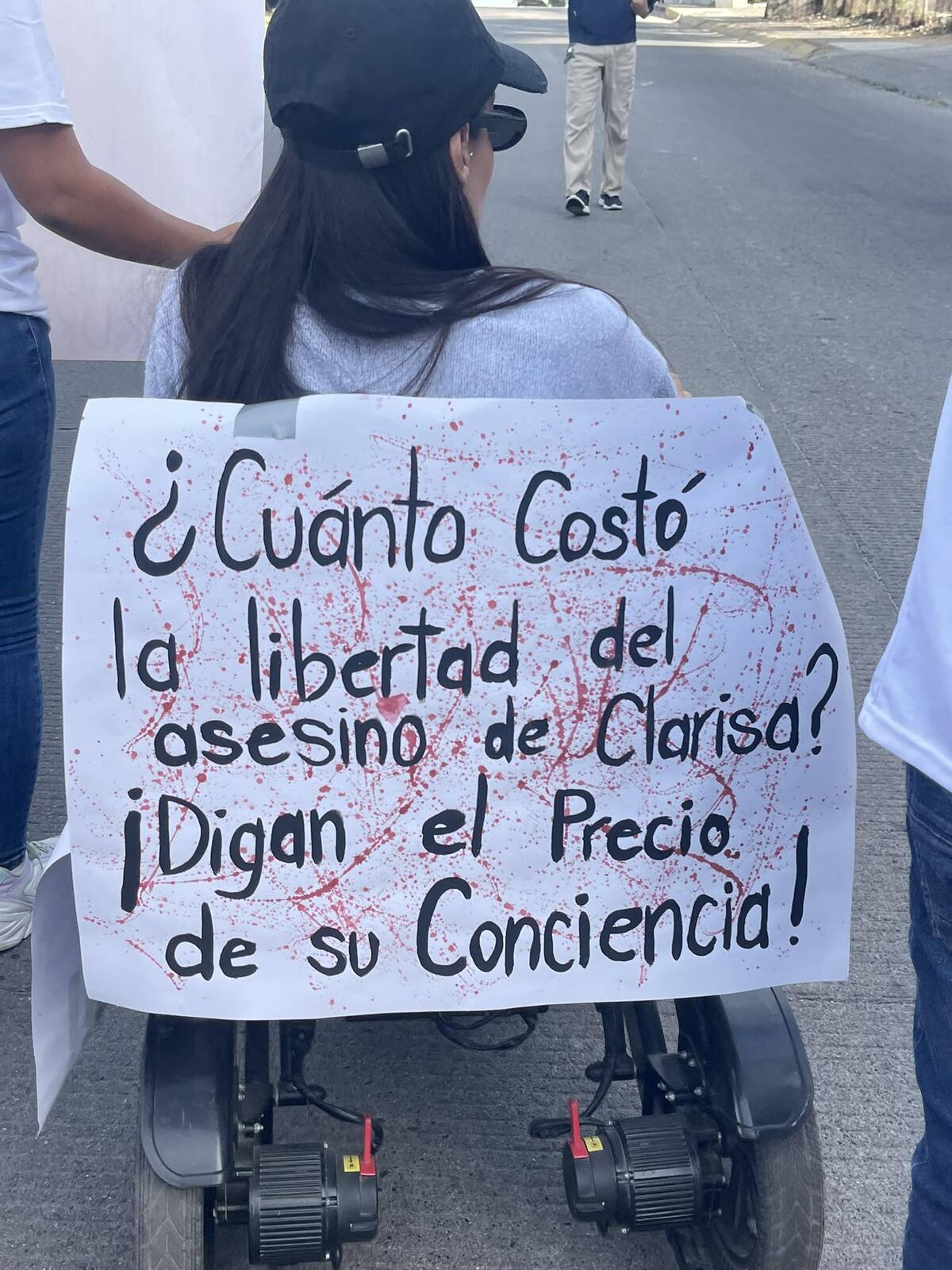 Mujer en silla de ruedas con una cartulina durante la manifestación por el caso de Clarisa en Puerto Vallarta