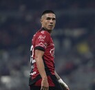 Un jugador del Atlas FC mira hacia atrás sobre su hombro en un estadio nocturno, vistiendo su camiseta rojinegra con patrocinios visibles.