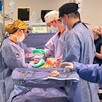 Médicos, enfermeras y asistentes realizando una cirugía de donación de órganos con equipo médico dentro de un quirófano