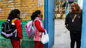 Se observan a dos niños con mochilas y una señora que está en una puerta.