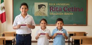 Pizarrón con la imagen de la beca Rita cetina y  en frente hay tres niños en un salón de clases que sostienen una tarjeta del bienestar