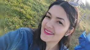 Clarisa Rodríguez viendo de medio perfil a la cámara mientras sonríe con unos lentes de sol en la cabeza y de fondo áreas verdes