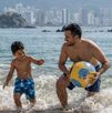 Familia disfrutando de las vacaciones de semana santa y jugando frente al mar de Acapulco con una pelota en un día soleado.