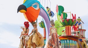 Hombres y mujeres arriba de un carro alegórico con la figura de un ave colorida en el Carnaval de Mazatlán