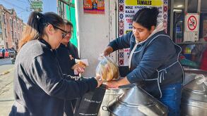 una mujer vendiendo tamales a una clienta en un puesto en la ciudad de puebla