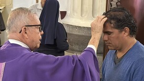 Sacerdote poniendo ceniza a una persona en la catedral