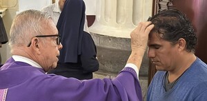 Sacerdote poniendo ceniza a una persona en la catedral