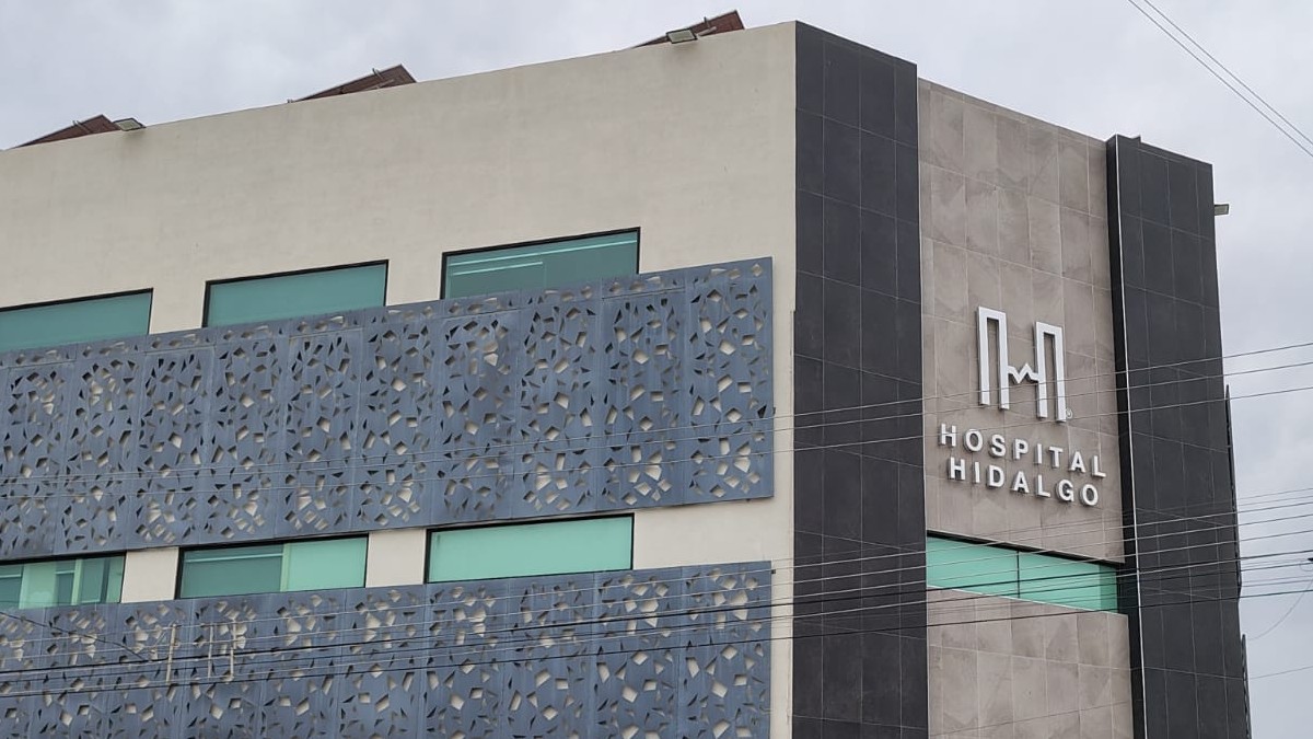 Edificio de varios pisos en color gris con letrero de Hospital