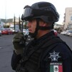 Oficial de la Guardia Civil en Michoacán hablando por un radio con casas, autos y edificios desenfocados de fondo